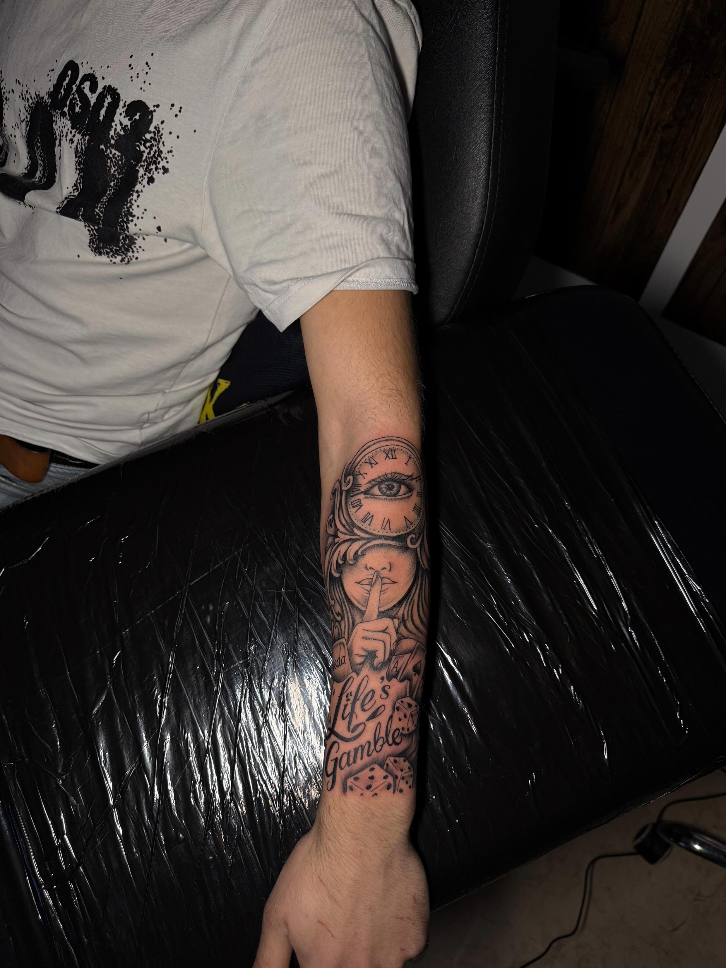 Uhr-Frau mit Lettering Life's Gamble Tattoo, Unterarm
